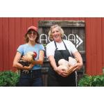 Image of 2 women holding chickens with AOOA logo on the barn in the back